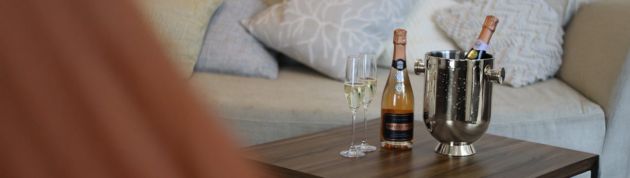 Bottle of champagne and a champagne bucket on a wooden table with a blurred background